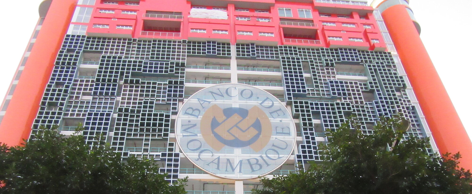 Gebäude der Bank de Maosambik mit Logo in der Mitte und 2 Bäumen links und rechts unten
