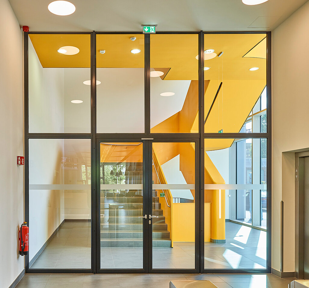 Flur mit Glaswand, Treppenhaus und Feuerlöscher links