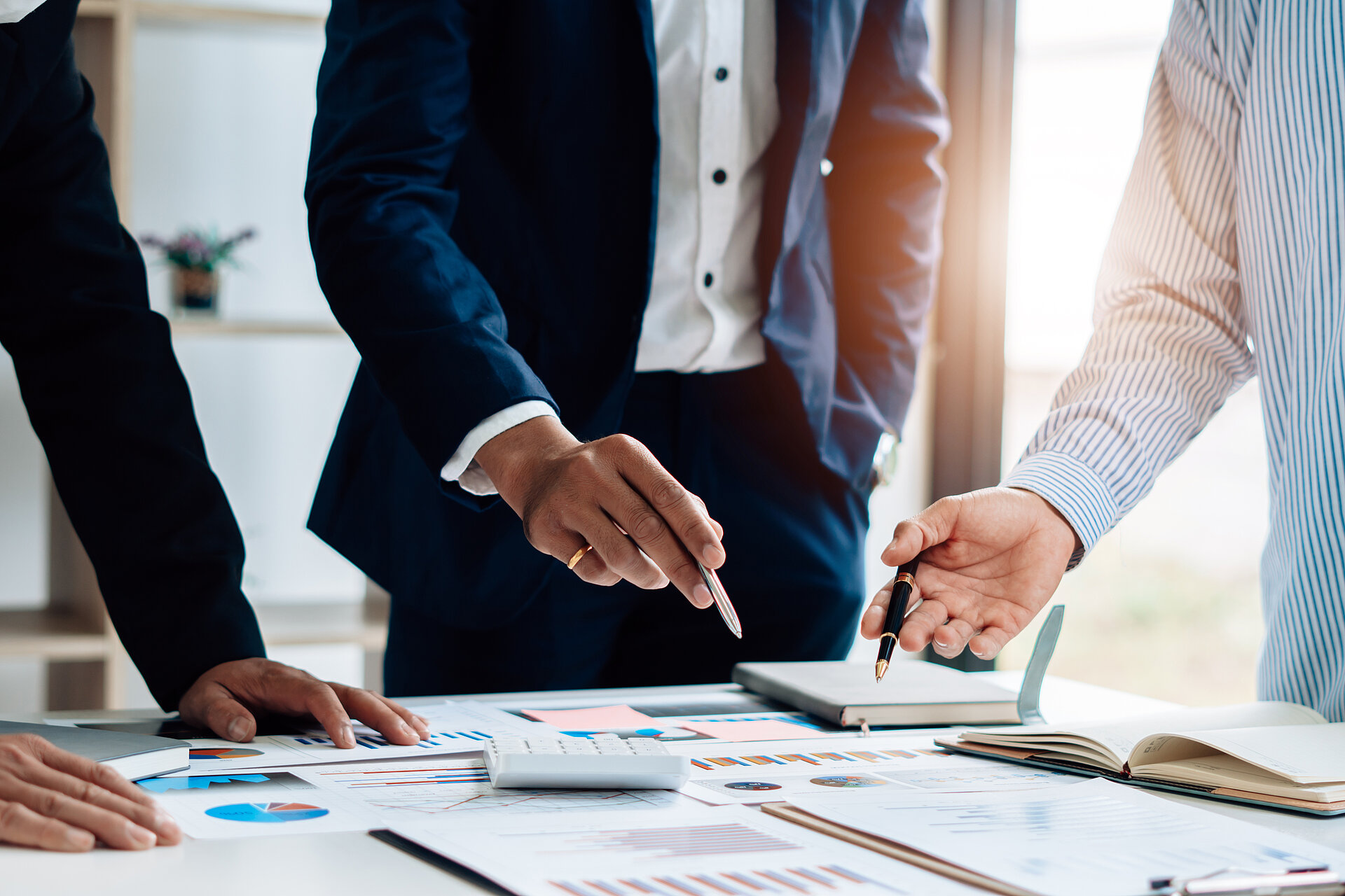 Drei Mitarbeiter stehen um einen Schreibtisch mit Unterlagen und plane die IT- und Rechenzentrumsstrategie