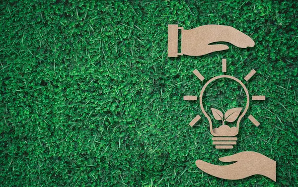 2 hands enclosing a light bulb on green background