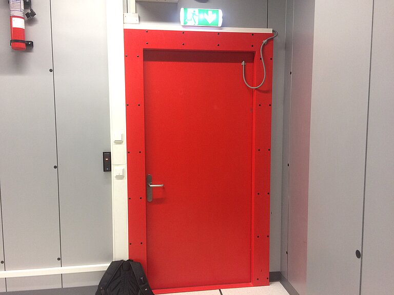 Rote Tür zum Rechenzentrum, darüber Fluchtweg-Hinweis-Schild