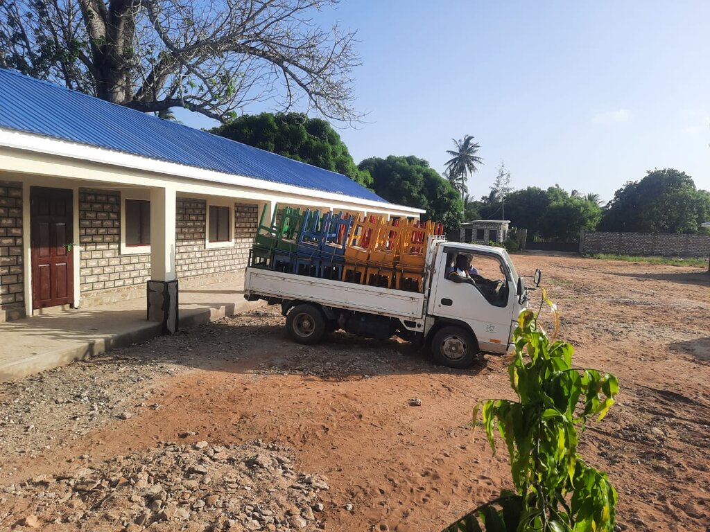 Transporter mit Schultischen vor der Schule, zwei Männer im Fahrzeug
