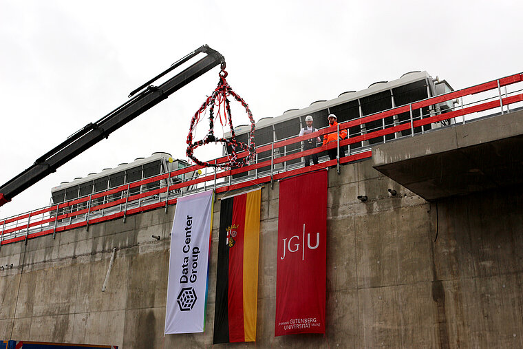 Roof of the computer center in Mainz with topping-out tree, flags of DCG, JGU and Germany, and 2 men on the roof reading something aloud