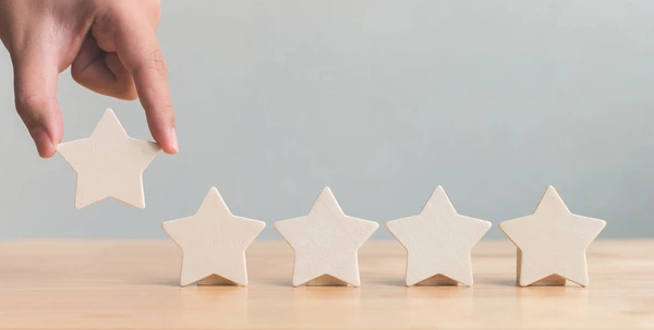 5 stars, 4 of which are placed on a table and the 5th star is placed on the table by a person