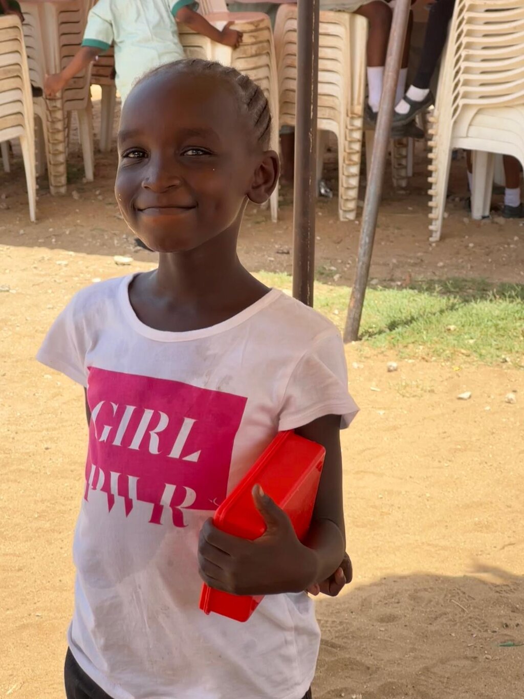 Strahlendes Kind mit Brotdose in der Hand.