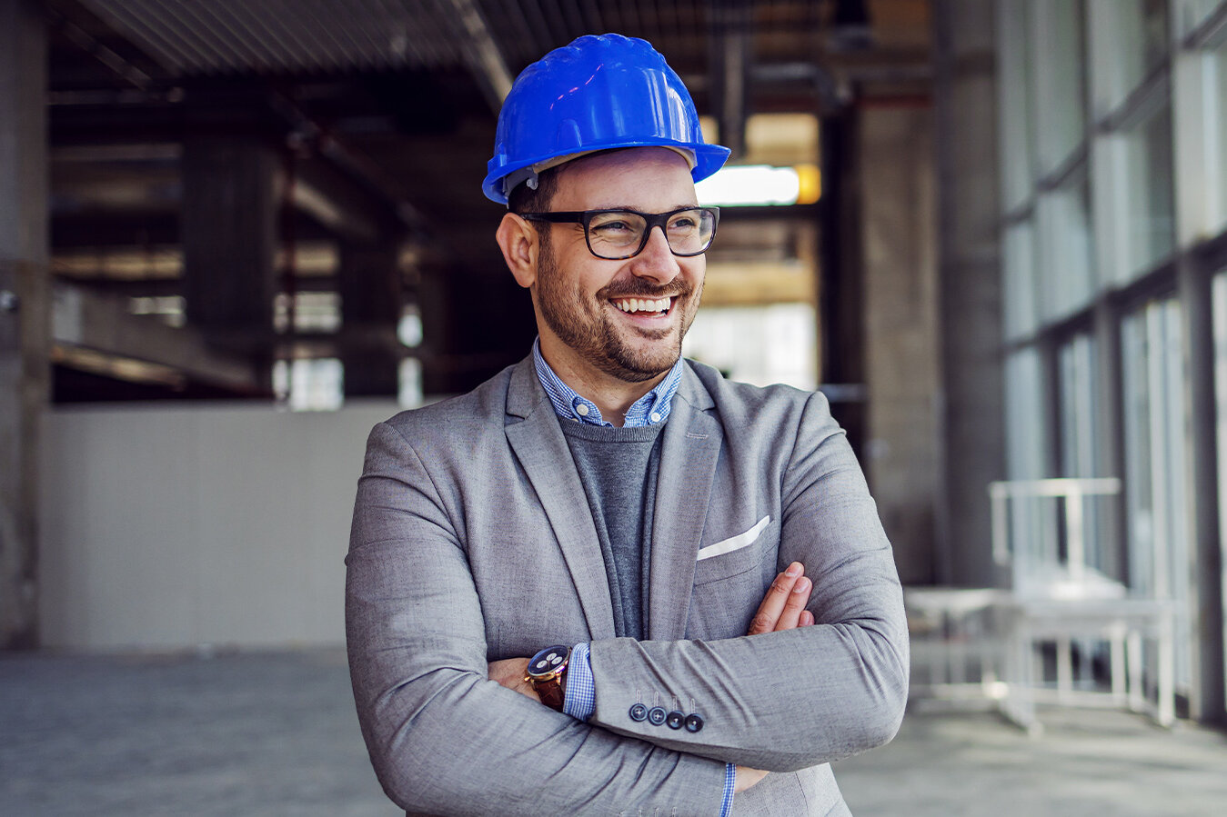 Smiling man with construction site helmet stands in almost empty room