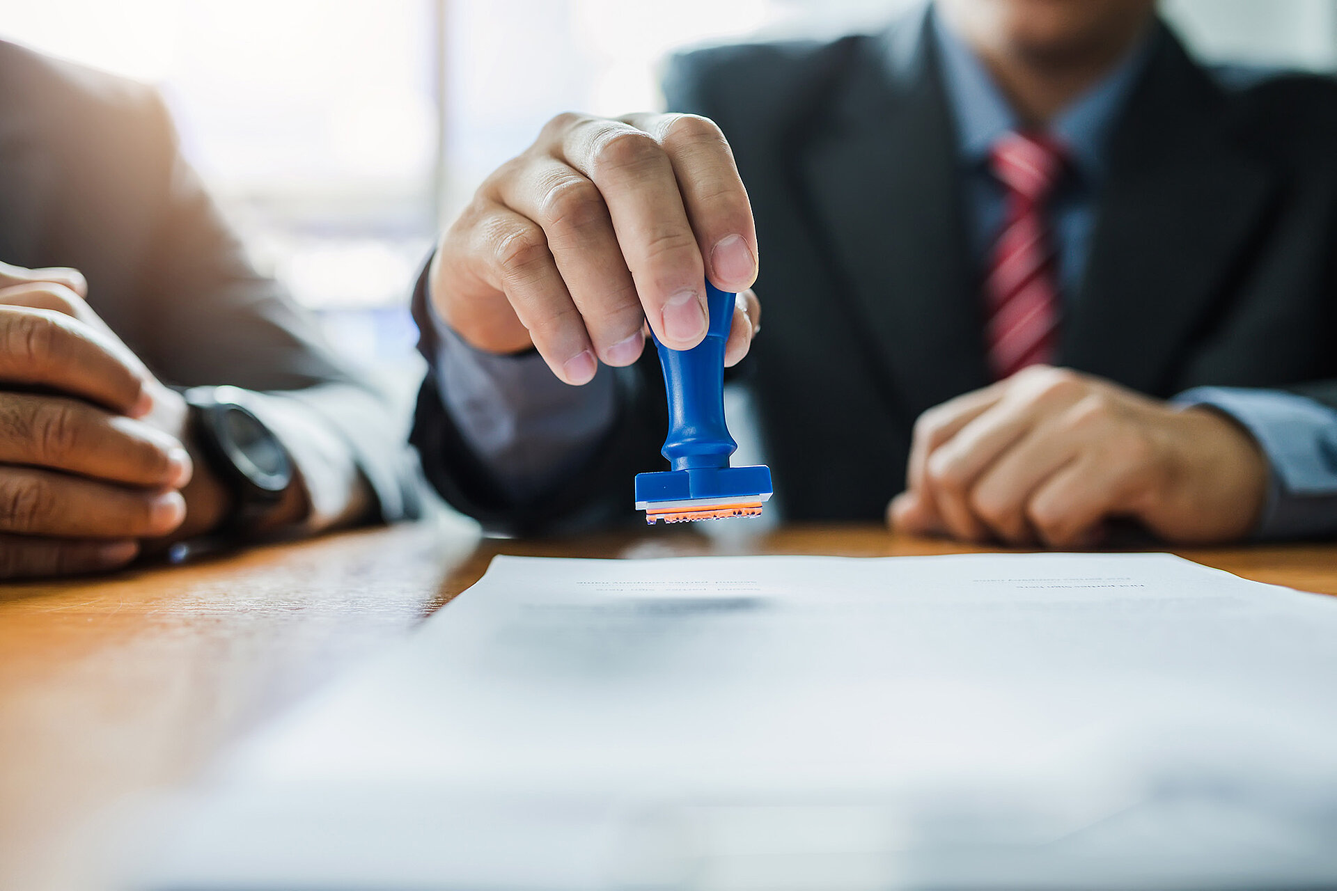 Ein Mann im Anzug setzt einen Stempel auf ein Blatt Papier