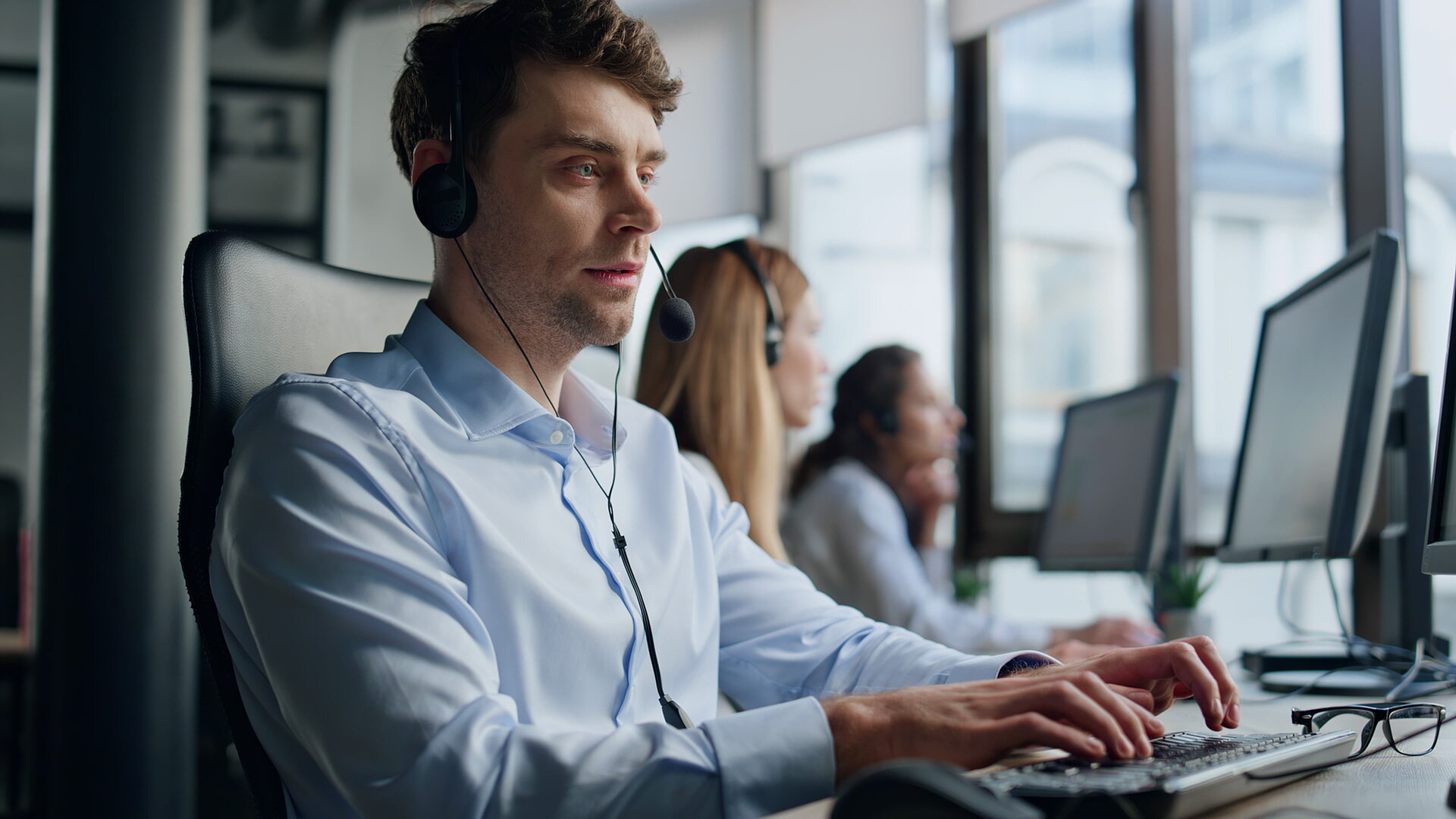 People in a call center at Pcs, wearing a headset and talking on the phone
