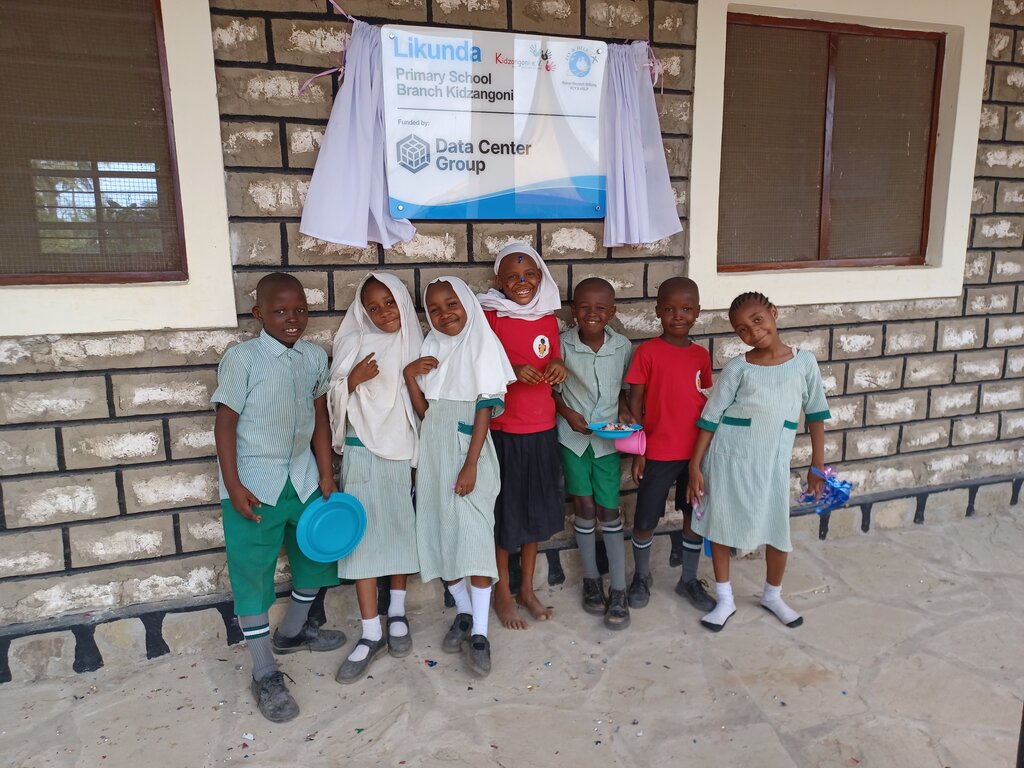 Ein paar Schulkinder stehen an einer Wand in einer Reihe.