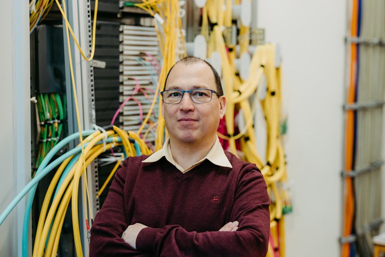 Gregor Zimmermann, IT manager at OVGU, in front of the server room, from which various cables come