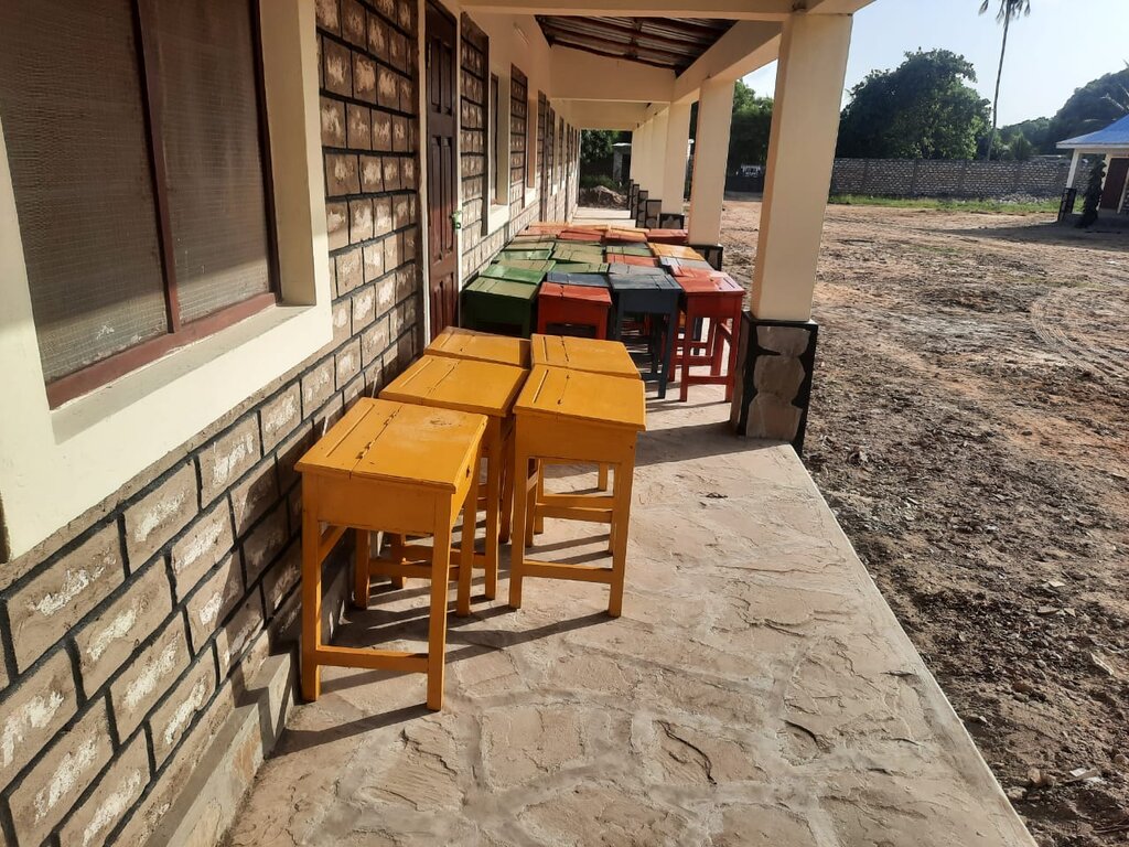 Schulgebäude mit bunten Schultischen in Gelb, Rot, Grün und Blau