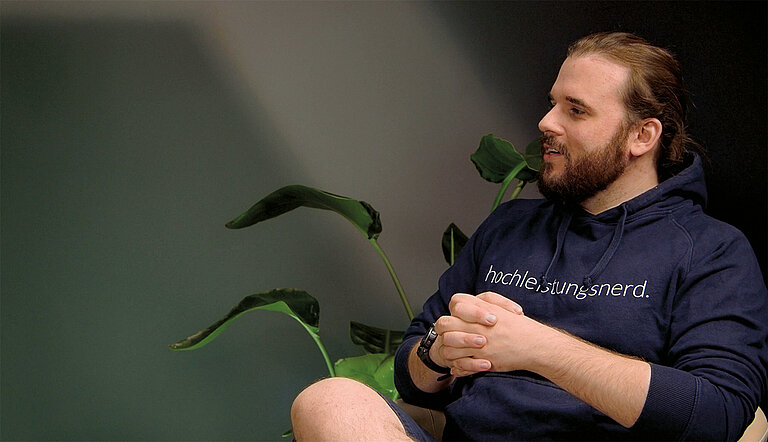 Daniel Menzel of Menzel IT GmbH during the interview next to a plant, gesticulating