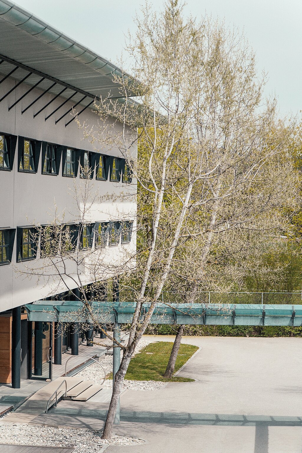 Gebäude von Marc O'Polo von der Seite. Haus mit Strauch und Eingangsbereich