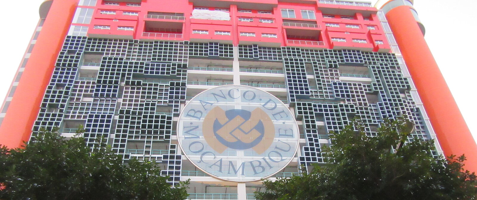 Building of Bank de Maosambik with logo in the middle and 2 trees left and right below