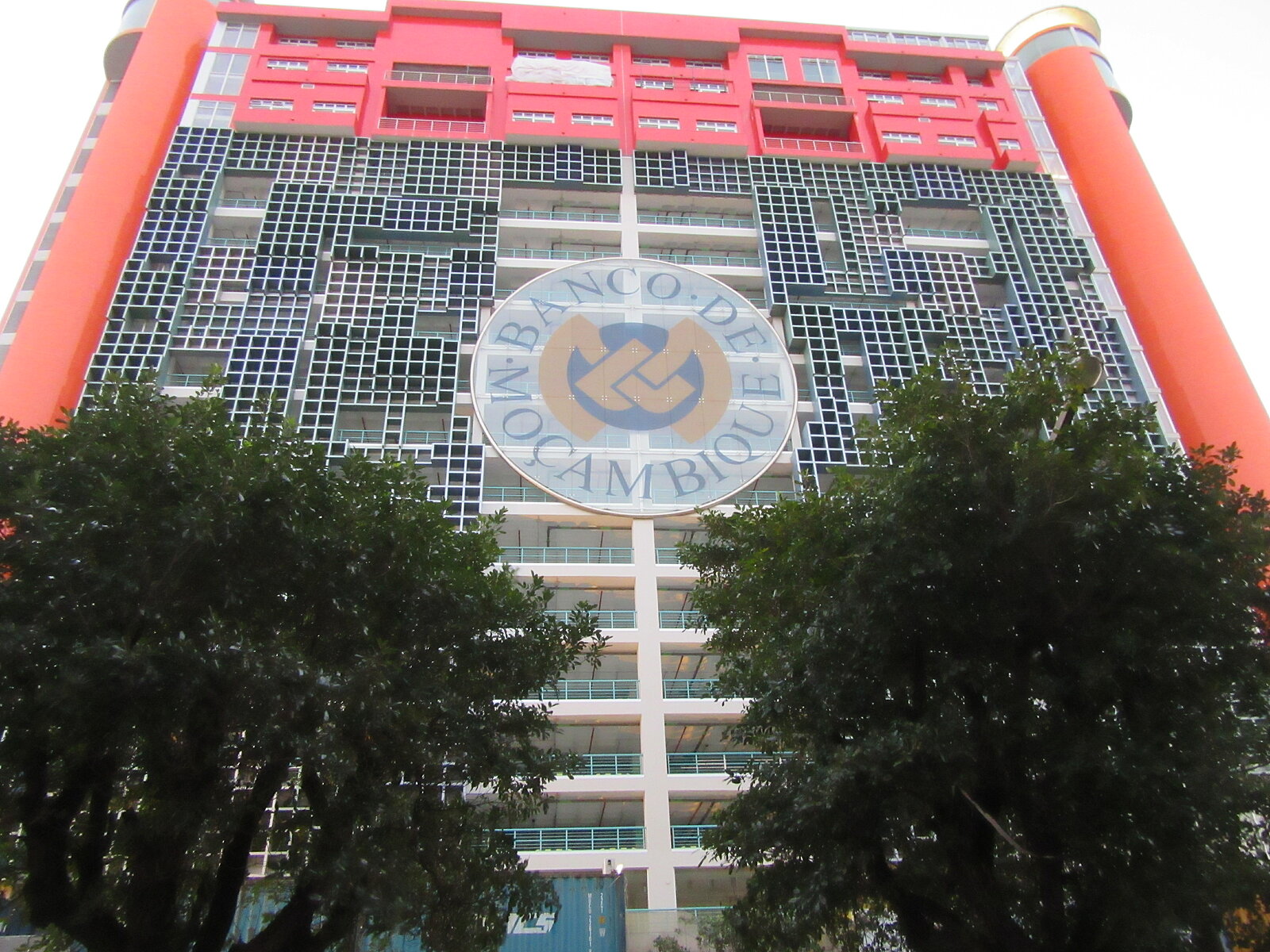 Building of Bank de Maosambik with logo in the middle and 2 trees left and right below