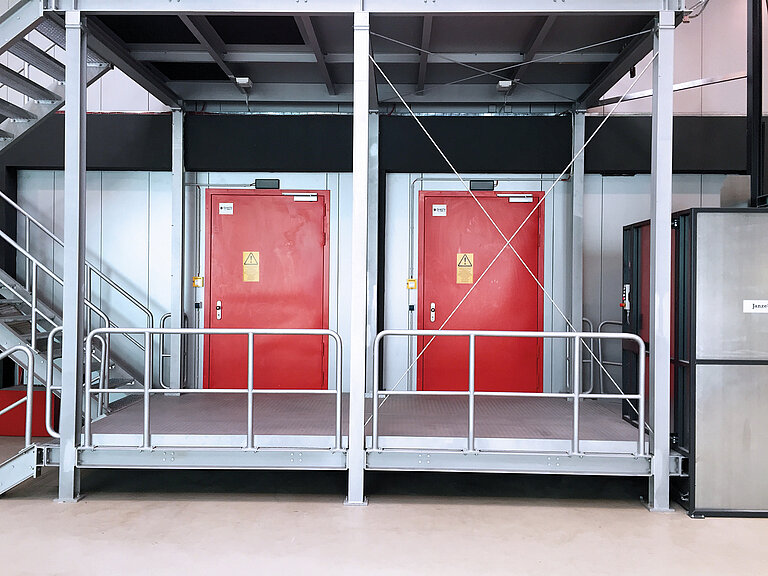 Eingangsbereich des Rechenzentrums mit 2 roten Türen und Treppenaufgang