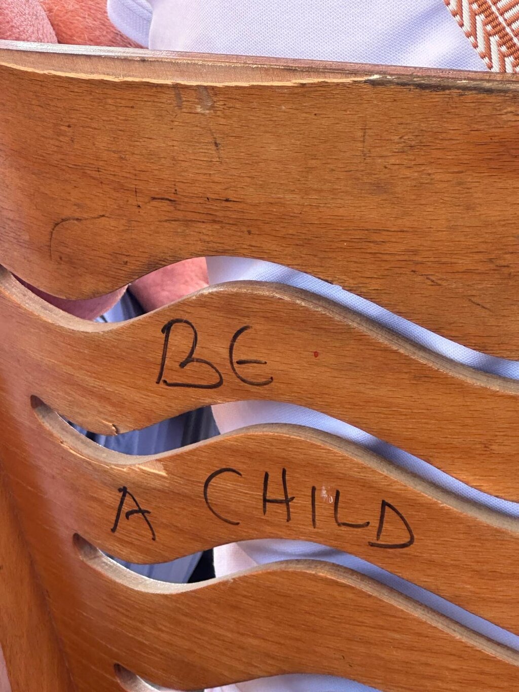 Auf einer Holzbank steht eingerizt :" Be a child"