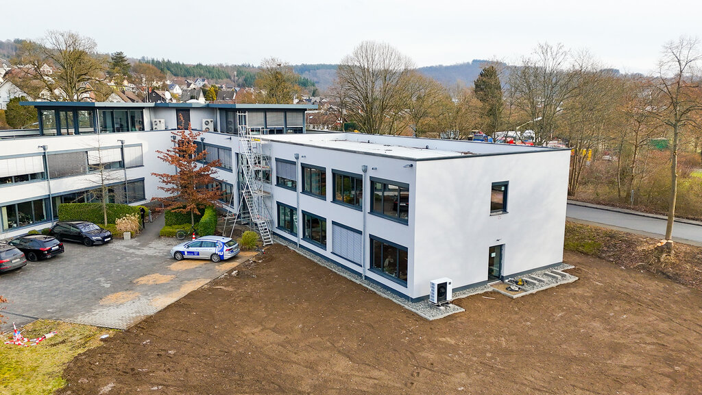 Firmengebäude der DCG aus der Luft mit parkenden Autos links und Erdfläche rechts