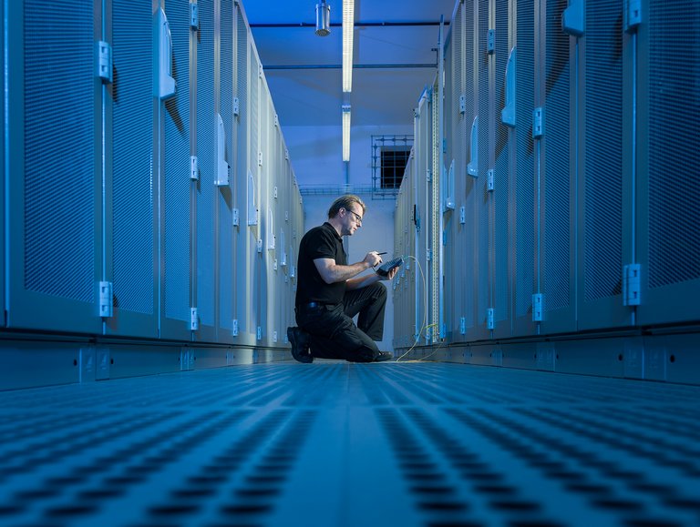 An employee at the Datacenter Leipzig, kneeling and inserting something into a device