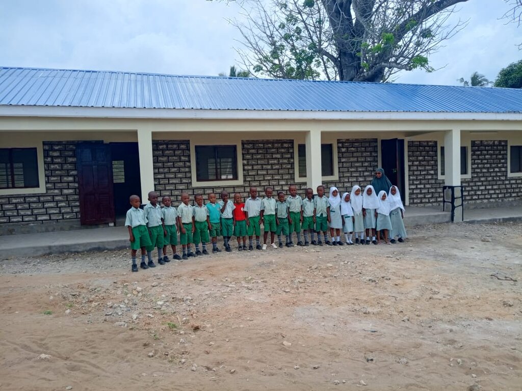 Kinder und Lehrerin vor dem fertiggestellten Schulgebäude