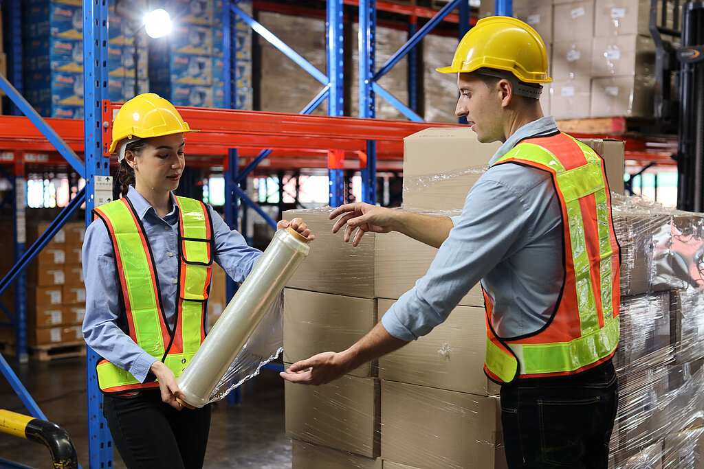 Man and woman in work clothes holding packaging in their hands