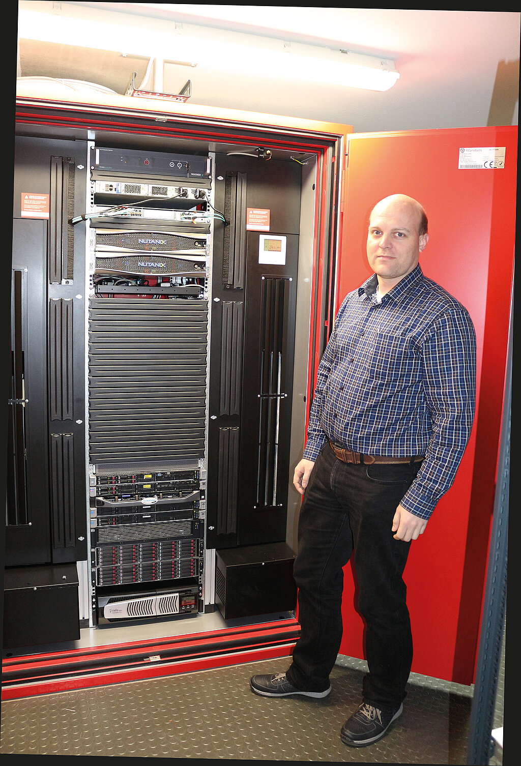 Mann vor geöffnetem DC IT Safe, in dem Serverracks zu sehen sind