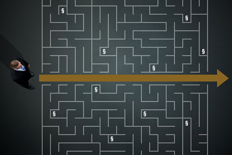 Labyrinth, in dem ein Pfeil in der Mitte den Weg weist und ein Mann, der darauf schaut. Dazu Parapgraphen-Zeichen