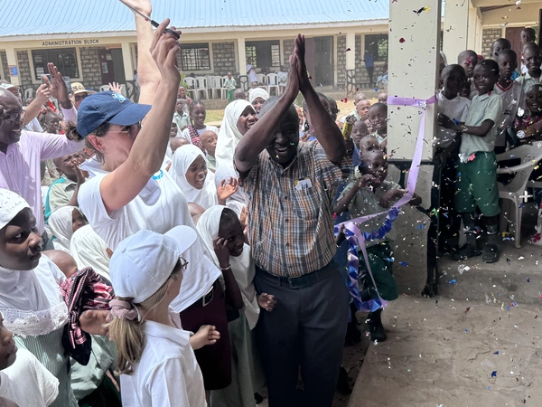 Children and adults cheer and clap; confetti flies