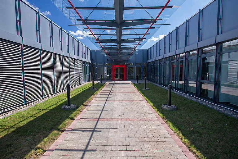 Eingangsbereich HDP mit Glasdach und roter Eingangstür