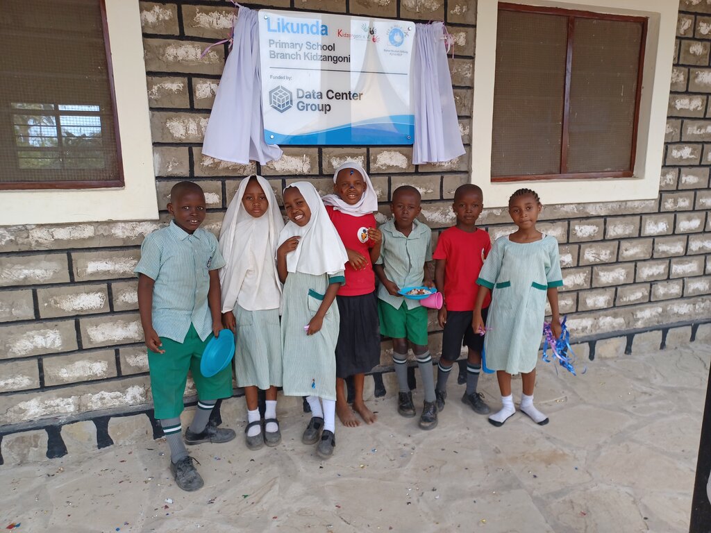 Ein paar Schulkinder stehen an einer Wand in einer Reihe.