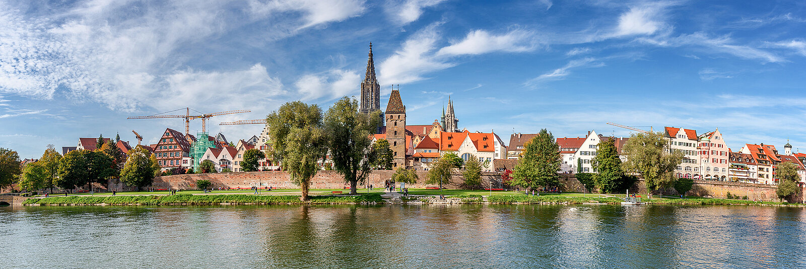 Stadtbild von Ulm mit Flüssen, einem Kirchturm, Häusern und Bäumen