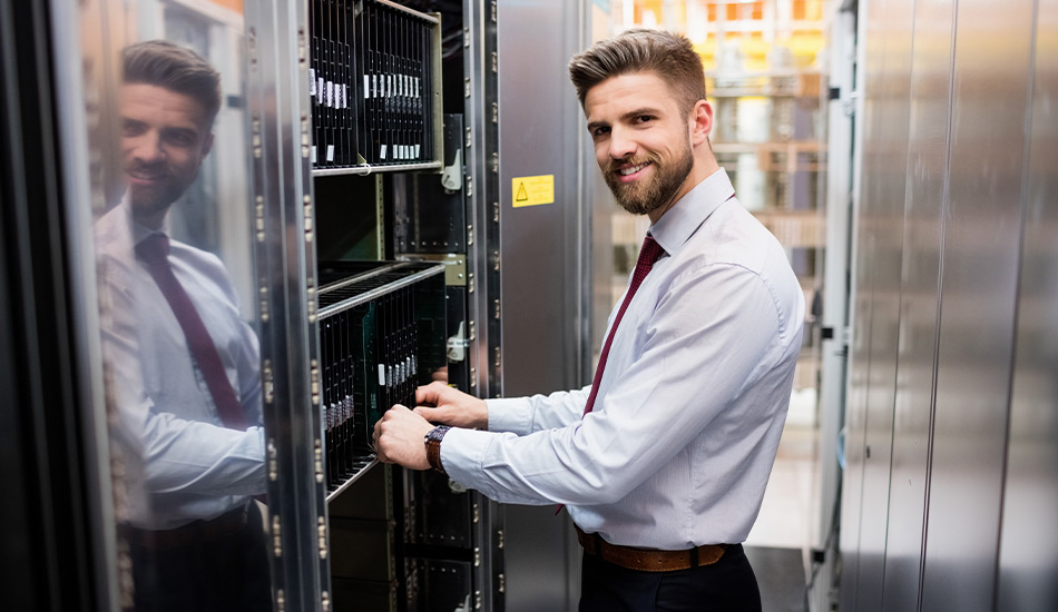 Smiling man in front of data center holding a server rack