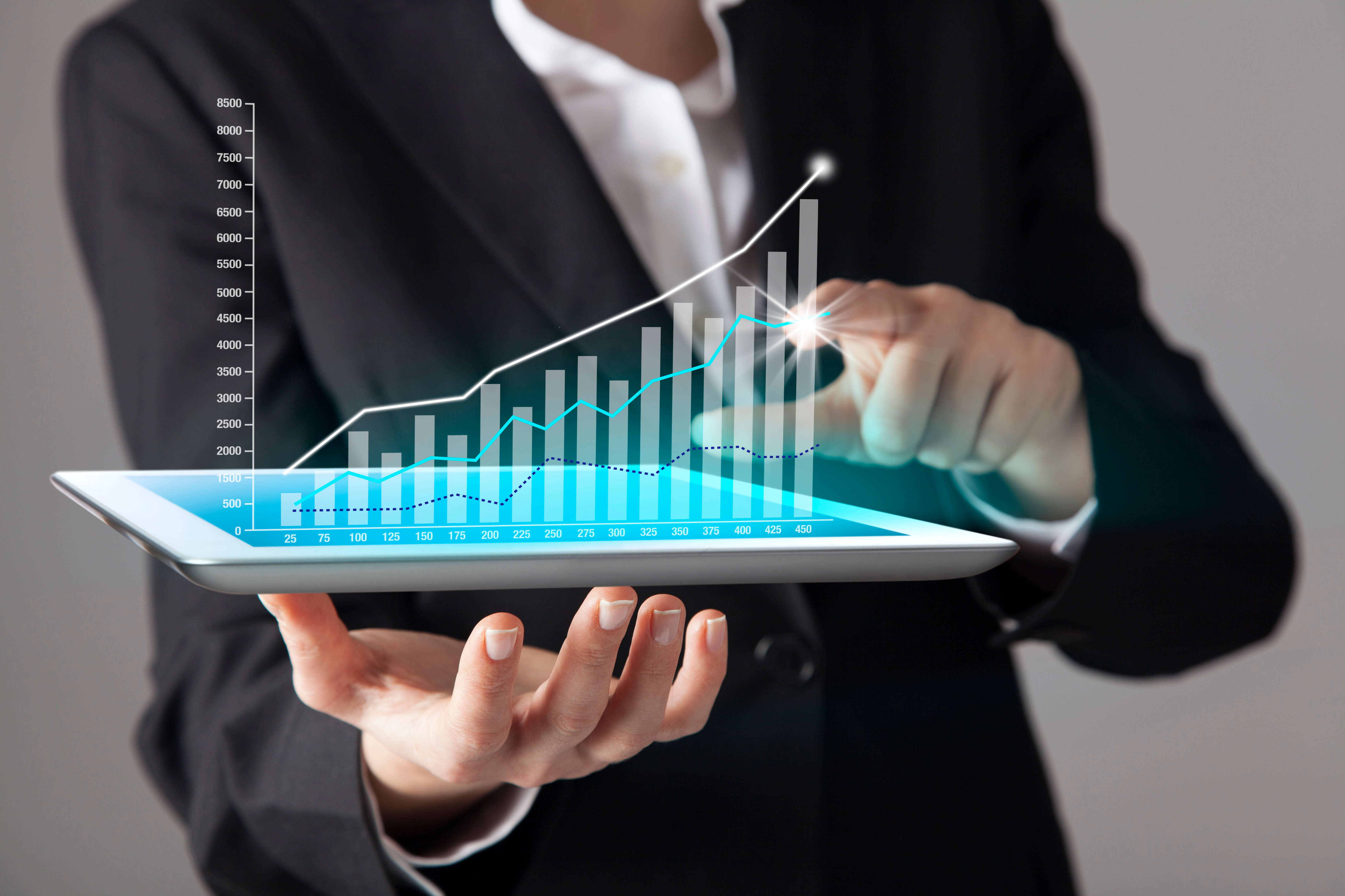A man in a suit holds a virtual graphic in his hand that shows a graph leading upwards