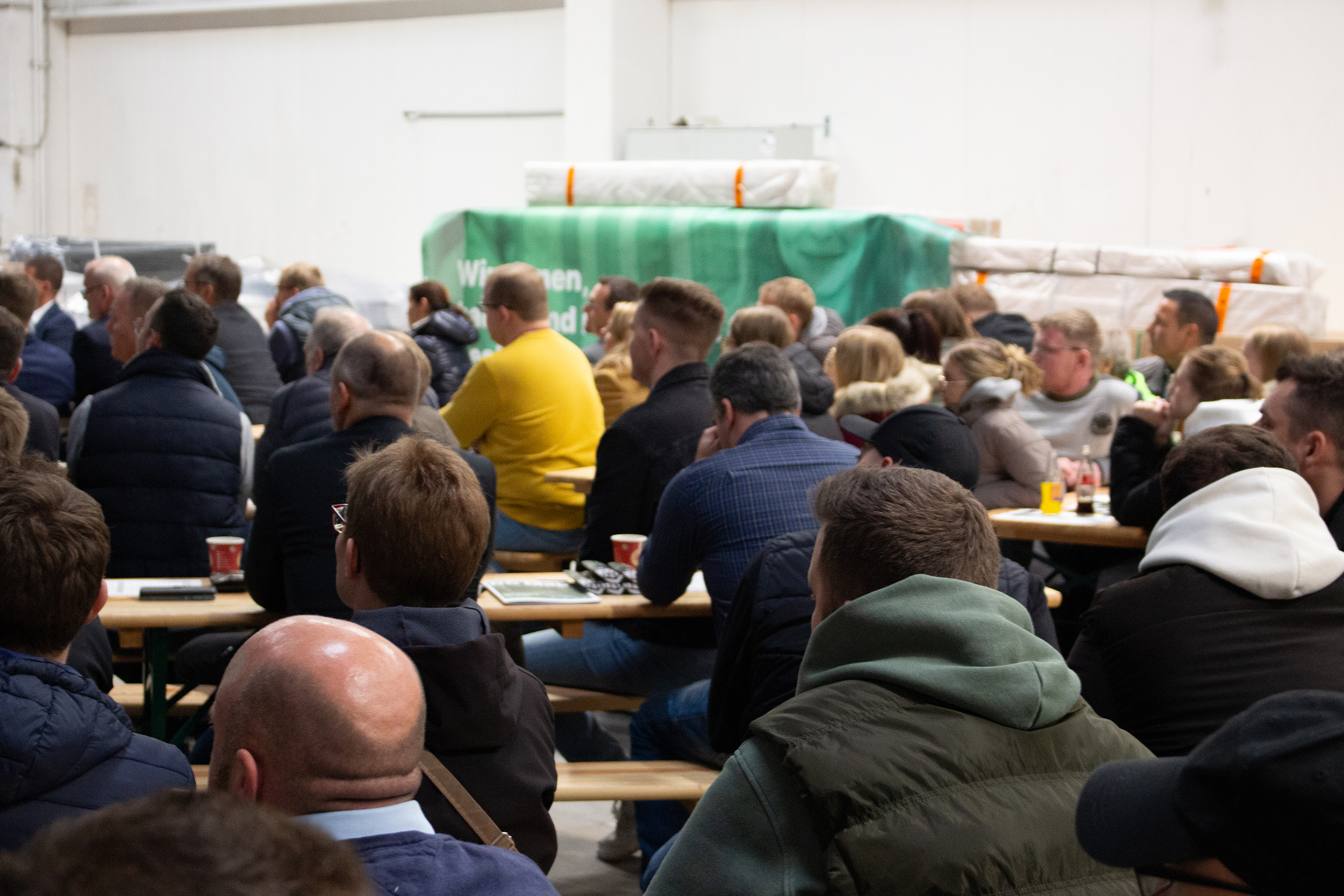 Die Belegschaft der DCG beim Kick-off in der Produktionshalle sitzend